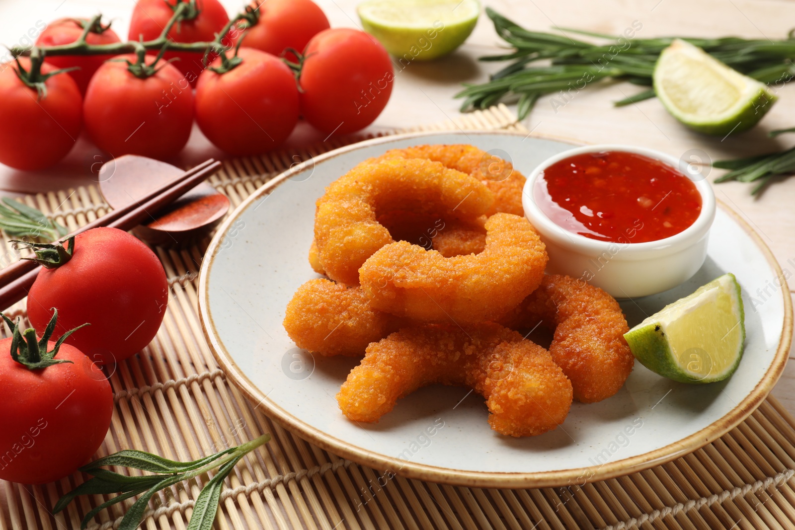 Photo of Tasty breaded fried shrimps served with lime and sauce on table