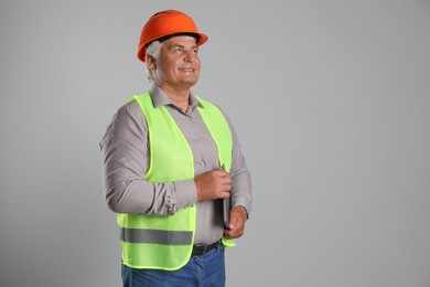 Photo of Engineer in hard hat with laptop on grey background, space for text