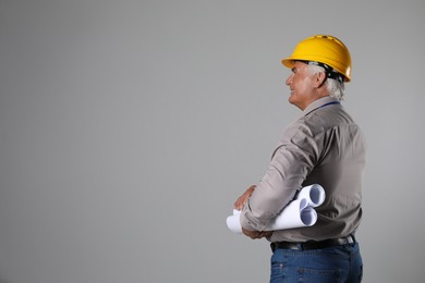 Engineer in hard hat with drafts on grey background, space for text