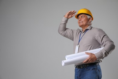 Photo of Engineer in hard hat with drafts on grey background, space for text