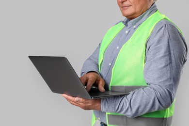 Engineer with laptop on grey background, closeup