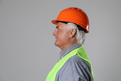 Engineer in hard hat on grey background, space for text