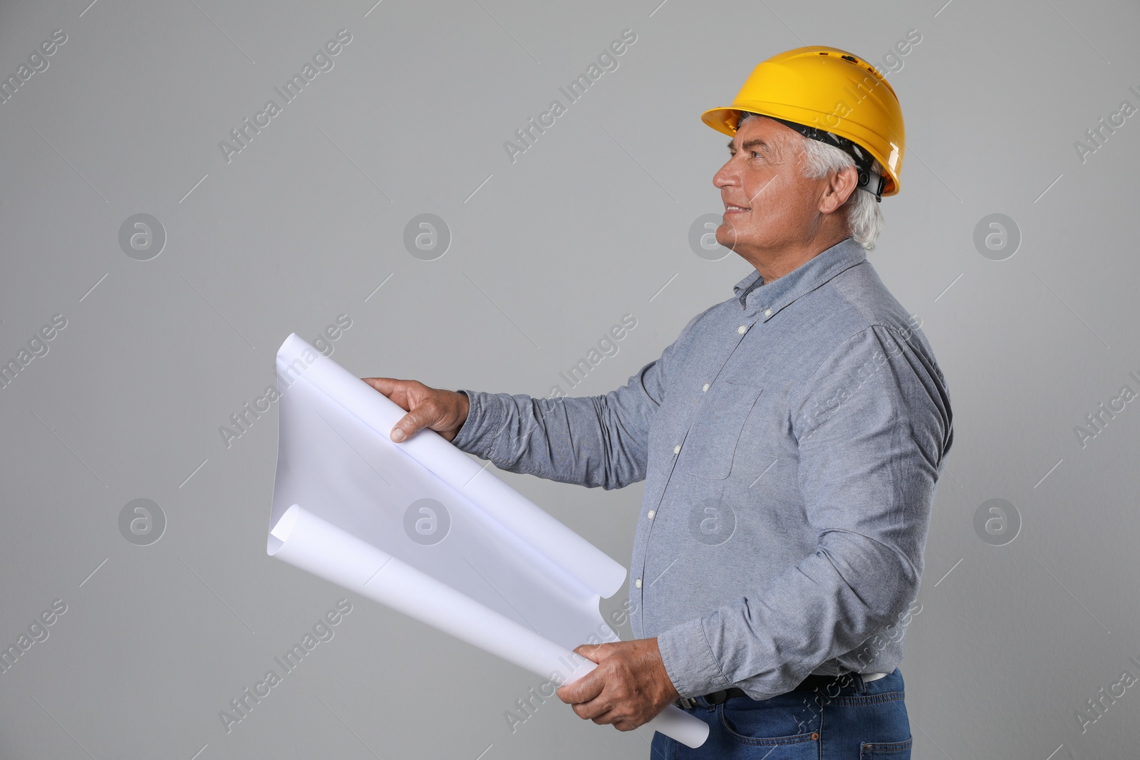 Photo of Engineer in hard hat with draft on grey background