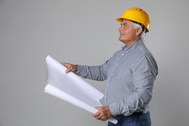 Engineer in hard hat with draft on grey background