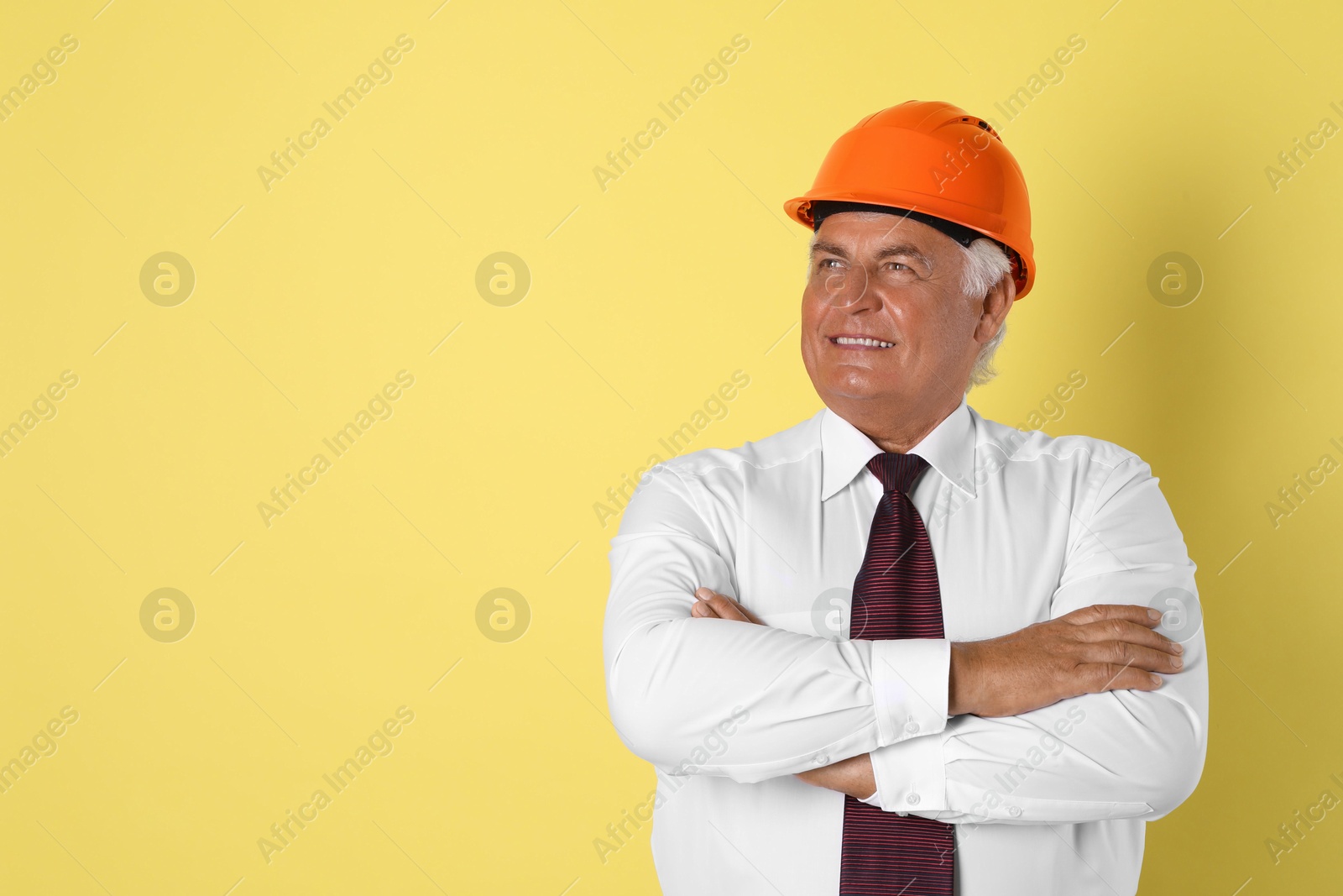 Photo of Engineer in hard hat on yellow background, space for text