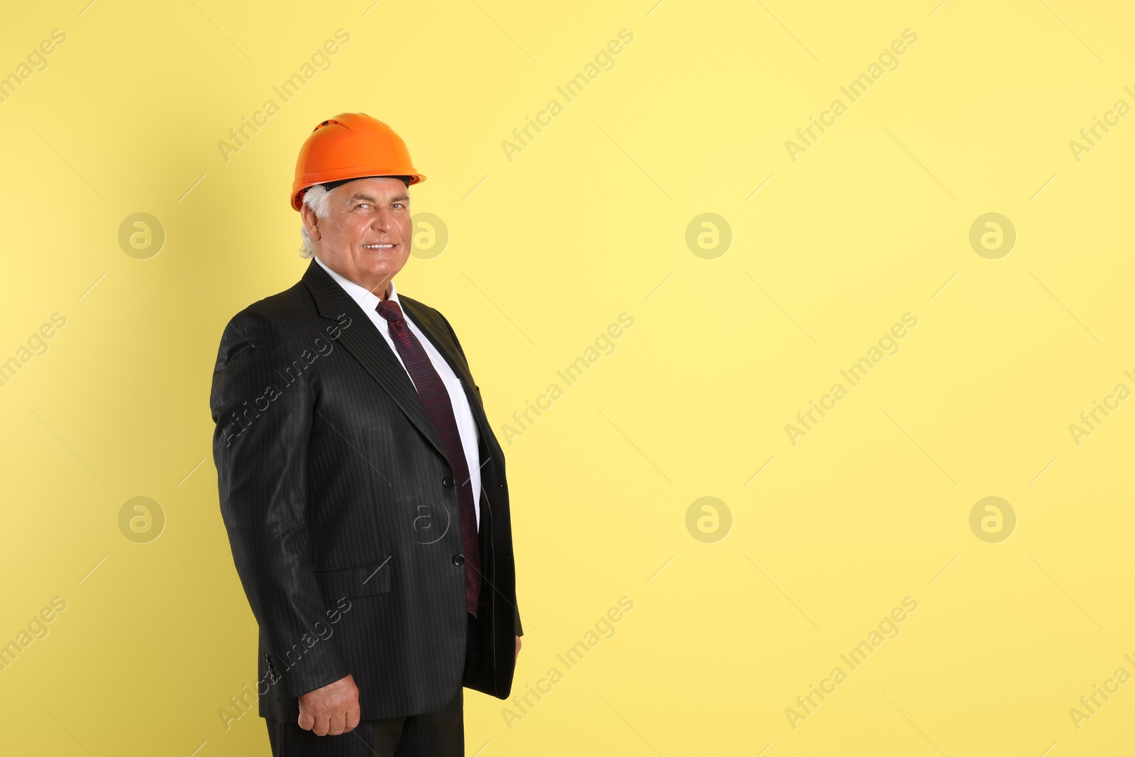 Photo of Engineer in hard hat on yellow background, space for text