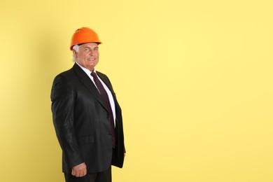 Photo of Engineer in hard hat on yellow background, space for text