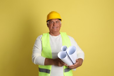 Engineer in hard hat with drafts on yellow background