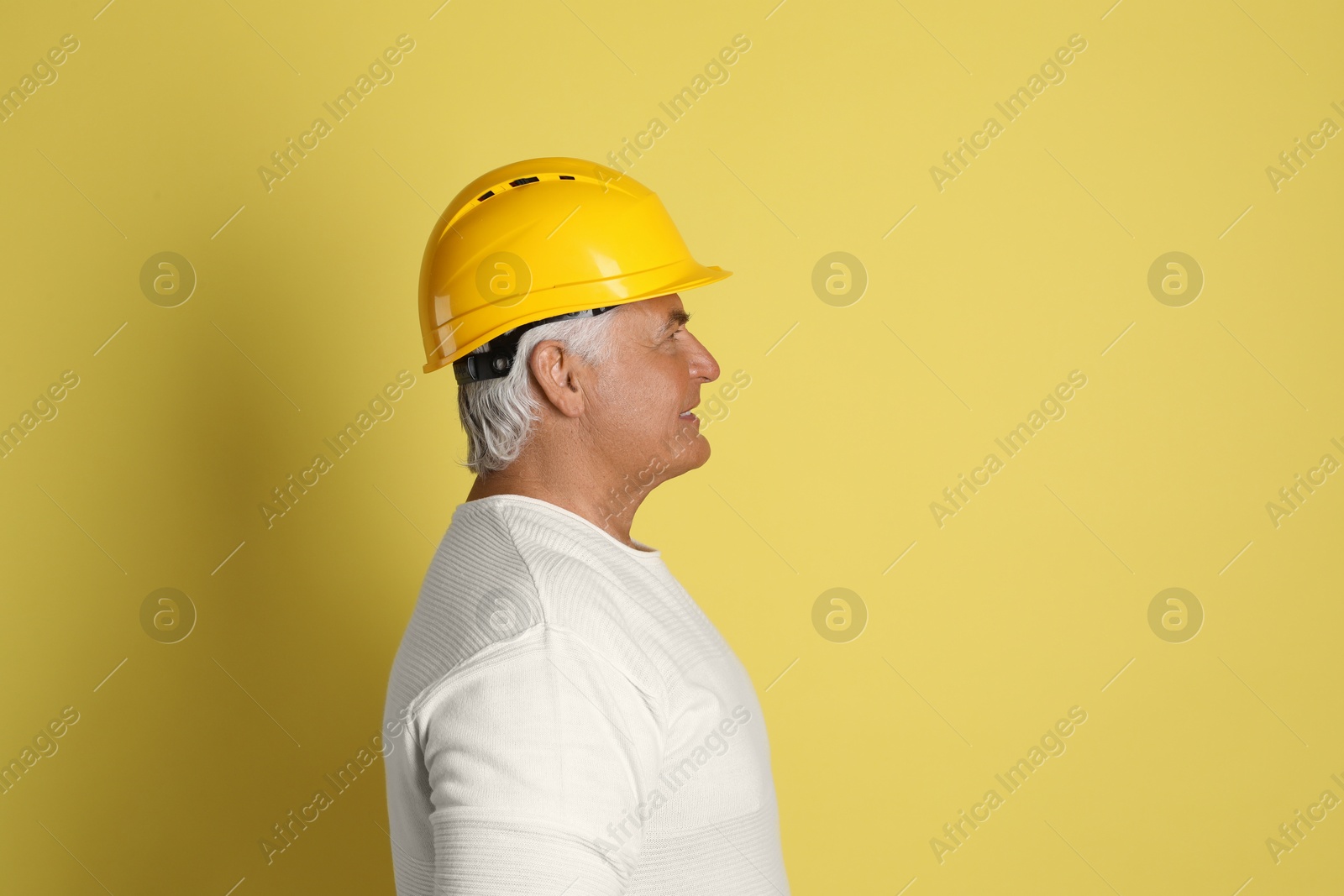 Photo of Engineer in hard hat on yellow background, space for text