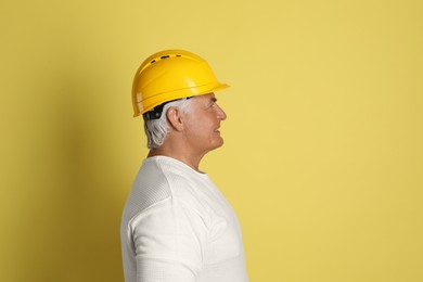 Photo of Engineer in hard hat on yellow background, space for text