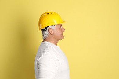 Photo of Engineer in hard hat on yellow background, space for text