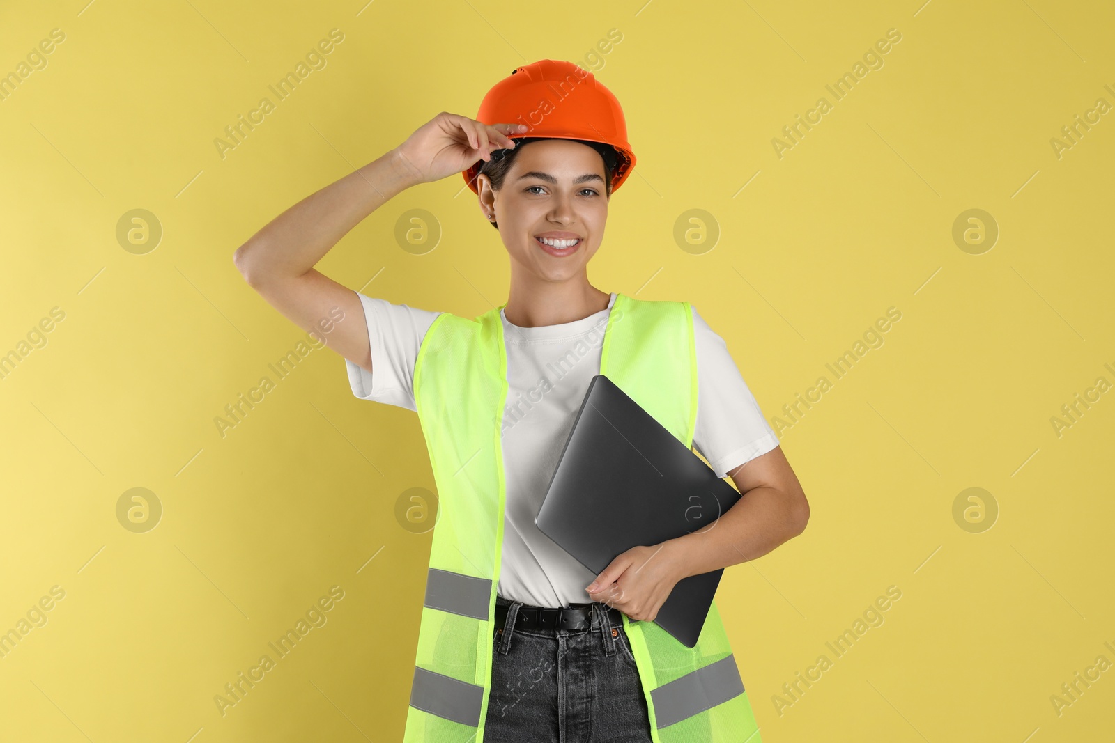 Photo of Engineer in hard hat with laptop on yellow background