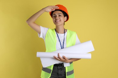 Photo of Engineer in hard hat with drafts on yellow background