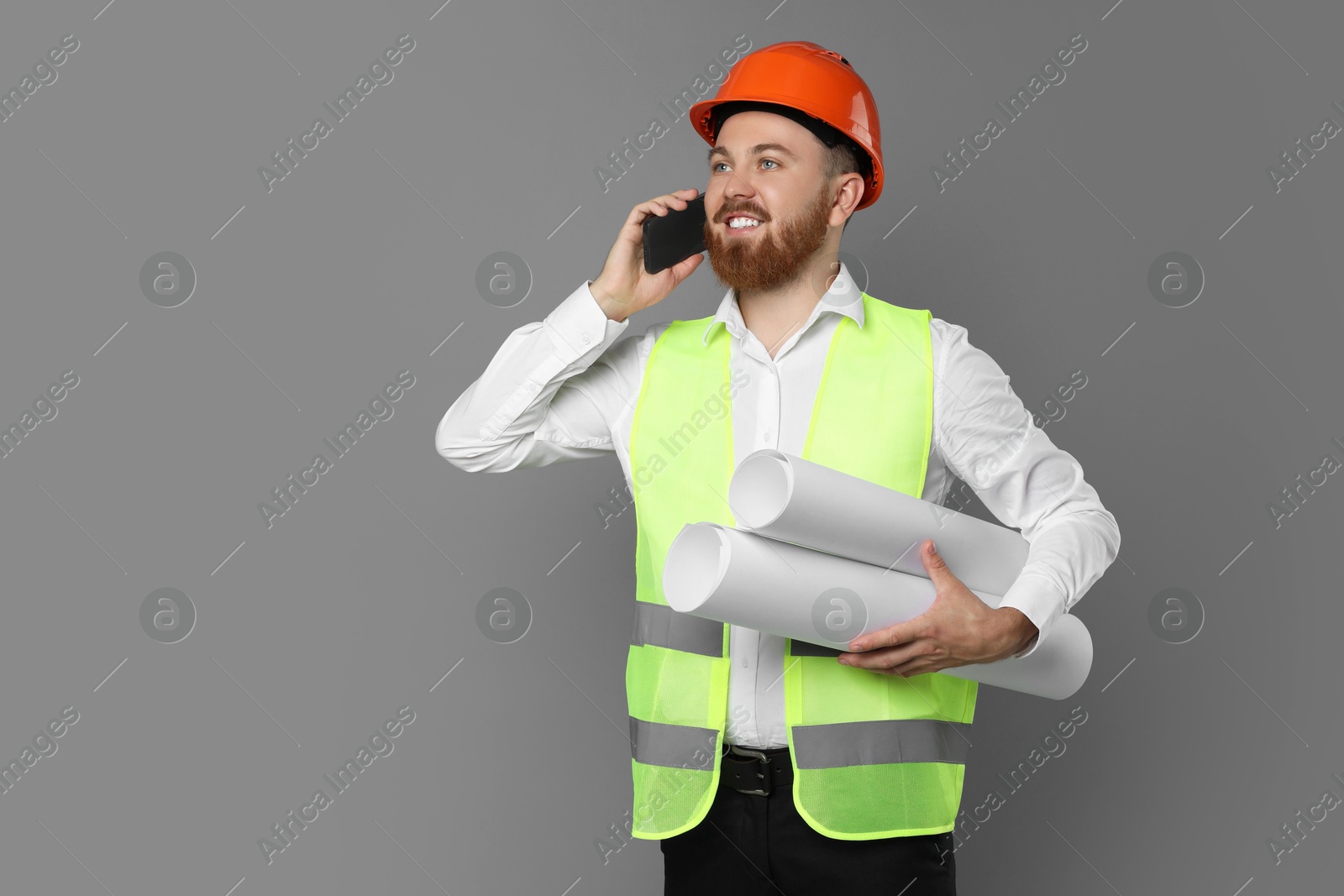 Photo of Engineer in hard hat with drafts talking on smartphone against grey background, space for text