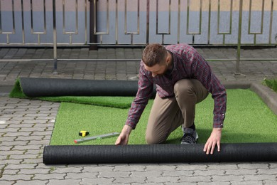 Young man installing artificial green turf outdoors