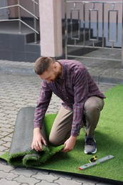 Young man installing artificial green turf outdoors