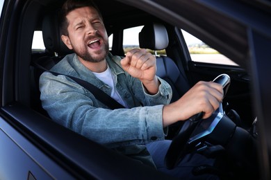 Man singing in car, view from outside