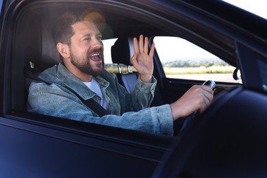 Photo of Man singing in car, view from outside