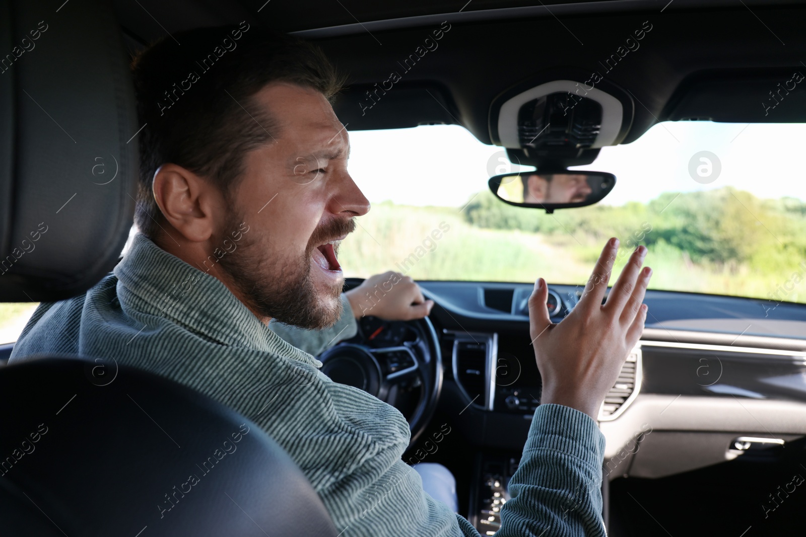 Photo of Man singing in car, view from inside