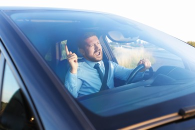 Photo of Man singing in car, view through windshield