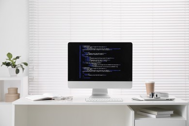 Programmer's workplace. Modern computer with unfinished code, coffee and supplies on desk