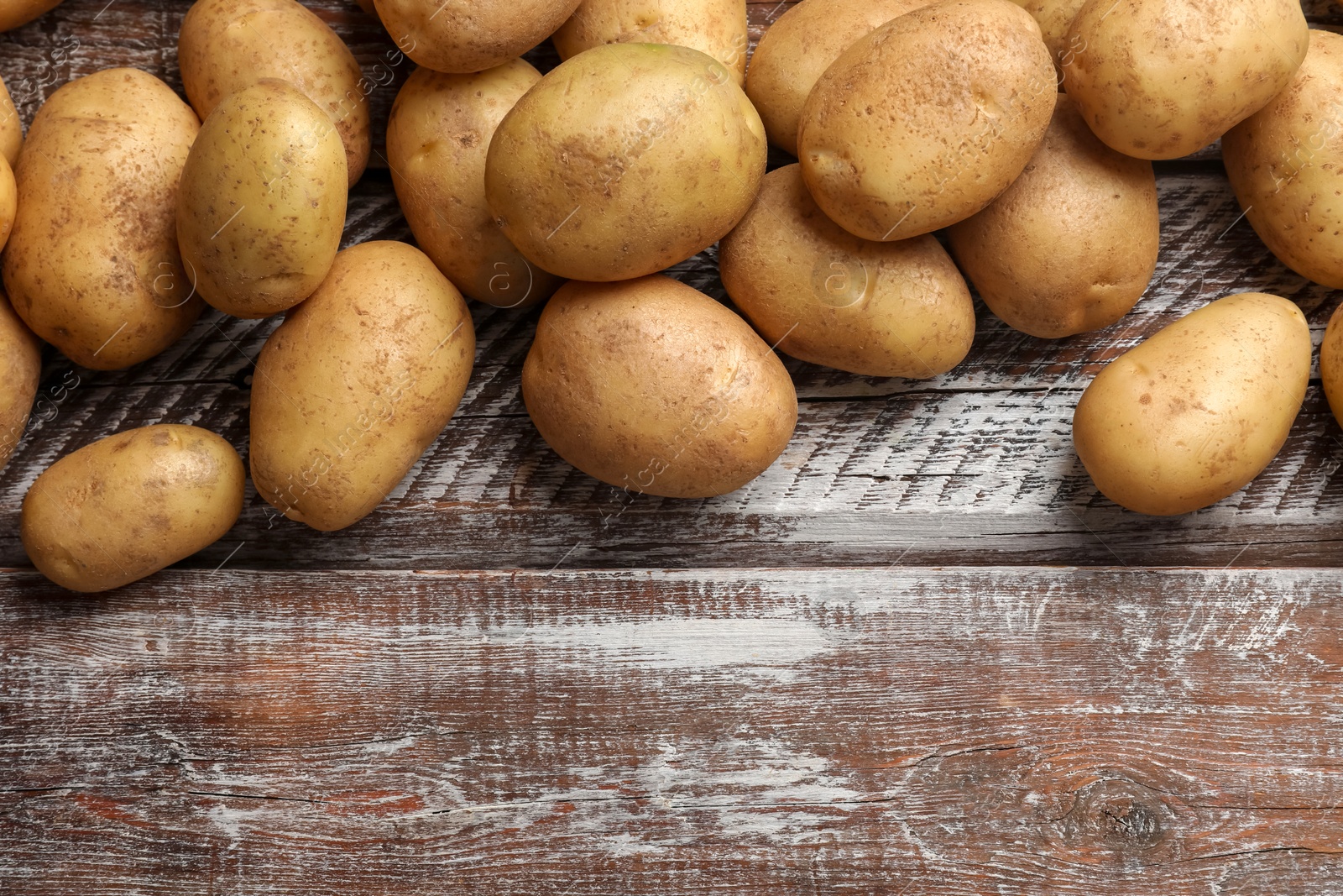 Photo of Many fresh potatoes on wooden rustic table, top view. Space for text