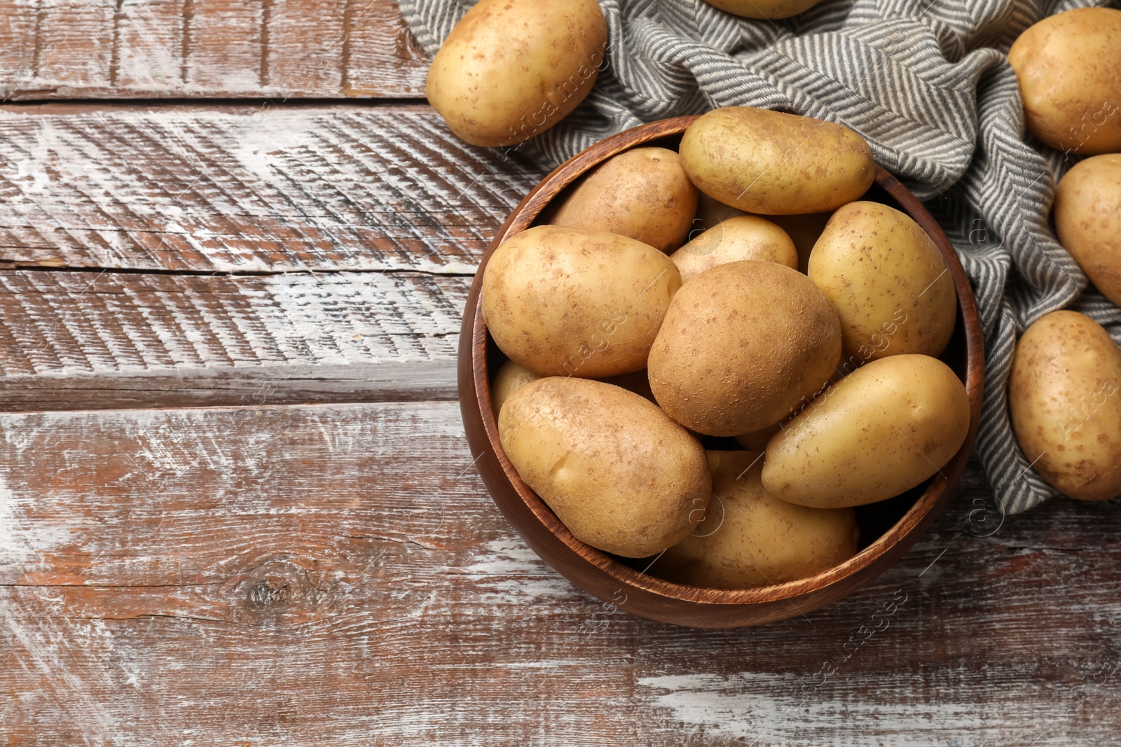 Photo of Many fresh potatoes on wooden rustic table, top view. Space for text