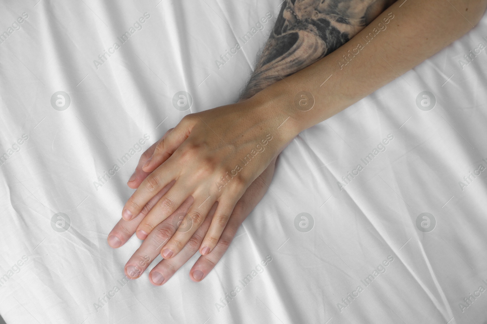 Photo of Lovely couple holding hands in bed, top view