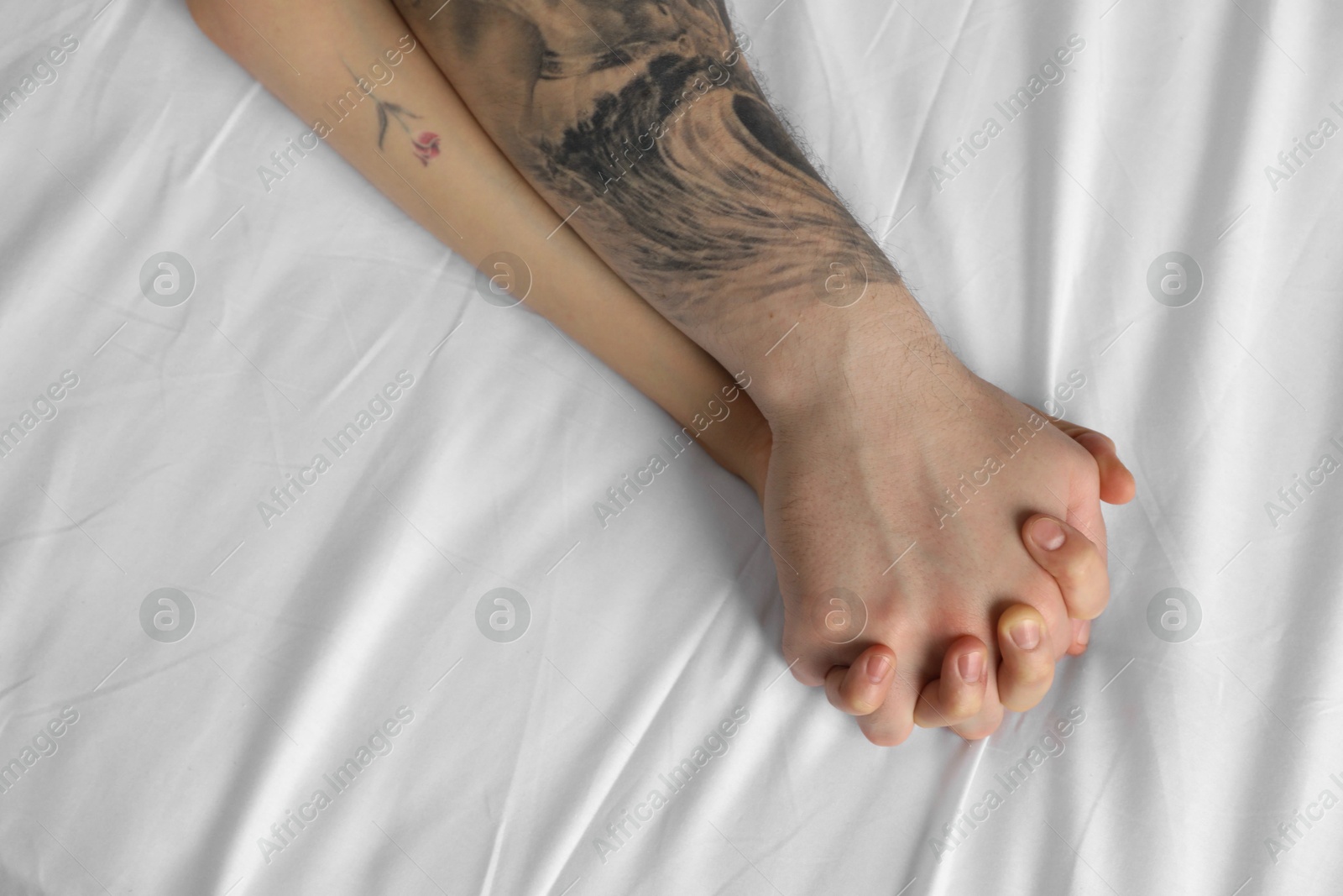 Photo of Lovely couple holding hands in bed, top view