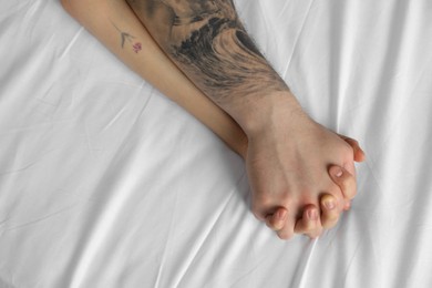 Photo of Lovely couple holding hands in bed, top view