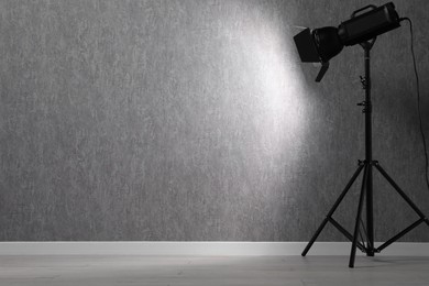 Grey photo background and professional lighting equipment in studio, space for text