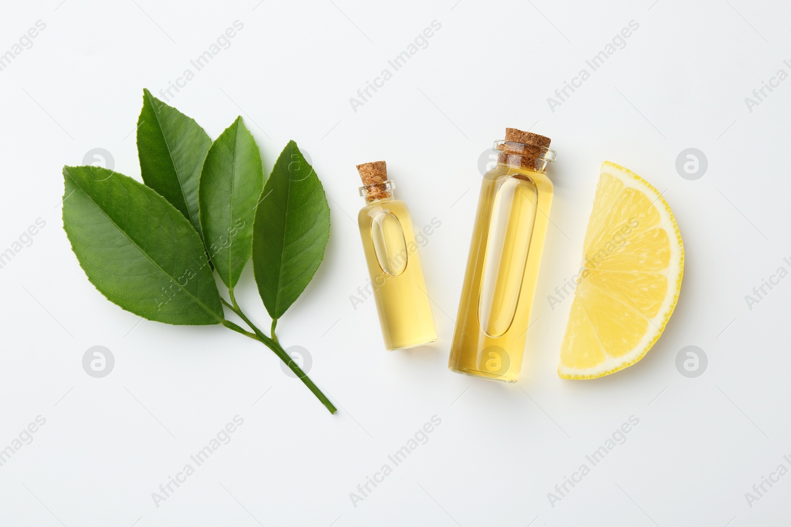 Photo of Bottles of essential oils, lemon and green leaves on white background, flat lay