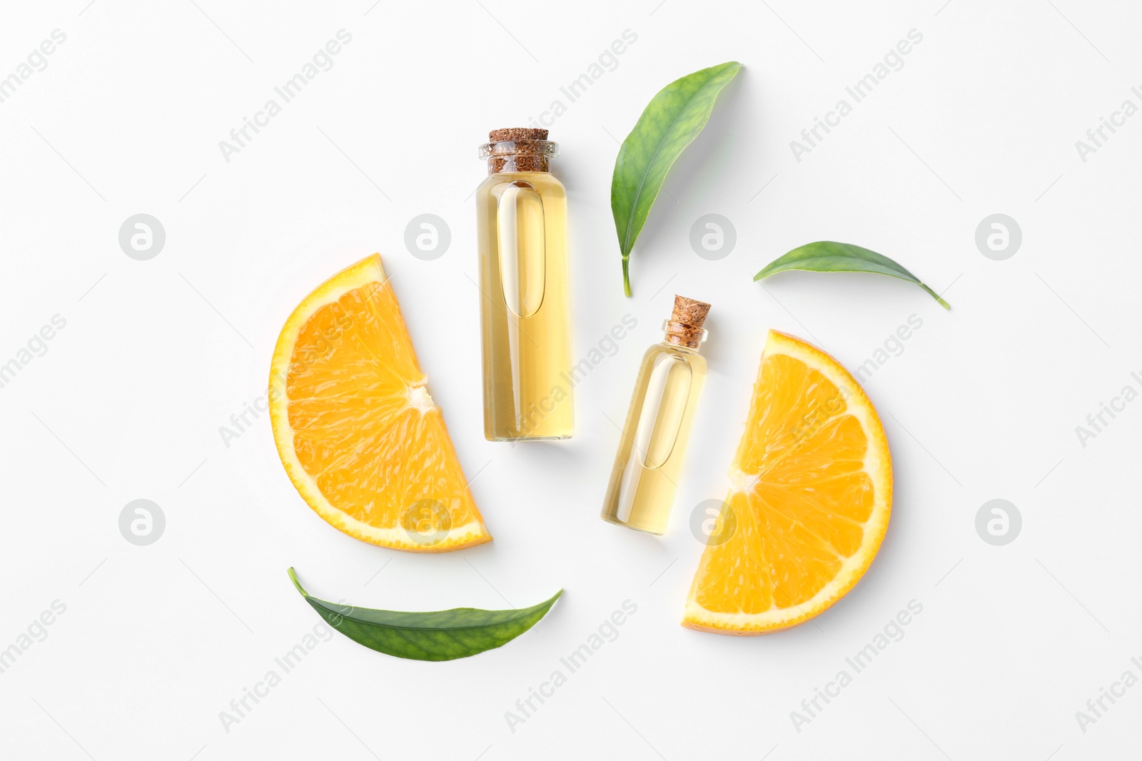 Photo of Bottles of essential oils, orange and green leaves on white background, flat lay