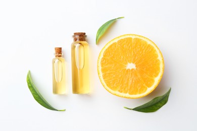 Photo of Bottles of essential oils, orange and green leaves on white background, flat lay