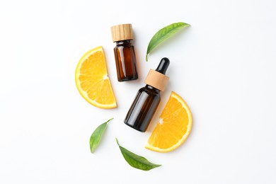 Bottles of essential oils, orange and green leaves on white background, flat lay