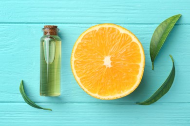 Photo of Bottle of essential oil, orange and green leaves on turquoise wooden table, flat lay