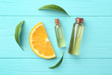 Photo of Bottles of essential oils, orange and green leaves on turquoise wooden table, flat lay