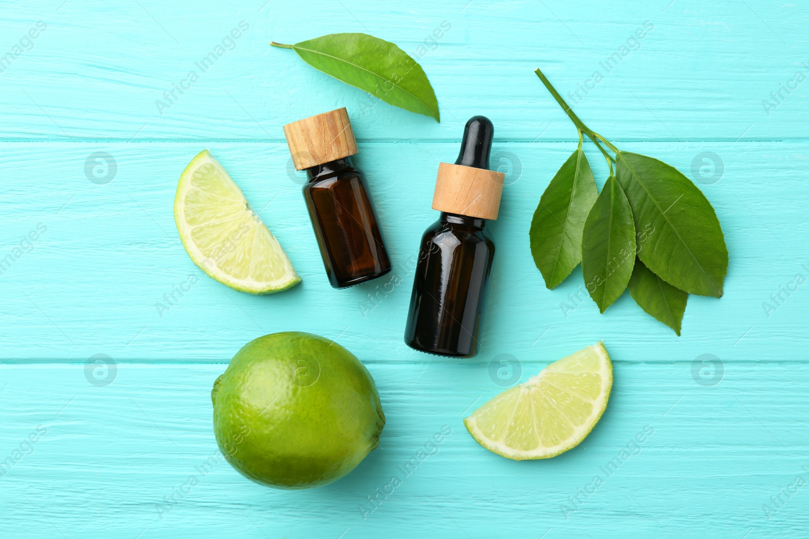 Photo of Bottles of essential oils, lime and green leaves on turquoise wooden table, flat lay