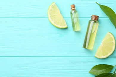 Photo of Bottles of essential oils, lime and green leaves on turquoise wooden table, flat lay. Space for text