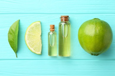 Photo of Bottles of essential oils, lime and green leaf on turquoise wooden table, flat lay