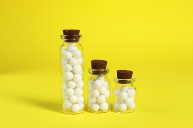 Photo of Bottles with homeopathic remedy on yellow background