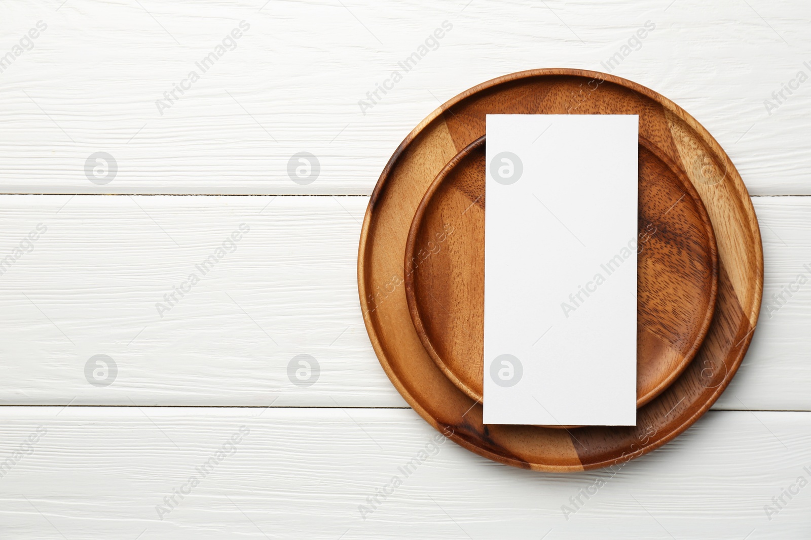 Photo of Empty menu and plates on white wooden table, top view. Mockup for design