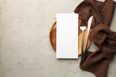 Photo of Empty menu, plate, cutlery and napkin on light grey table, top view. Mockup for design