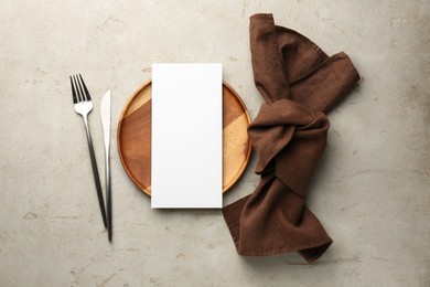 Empty menu, plate, cutlery and napkin on light grey table, top view. Mockup for design