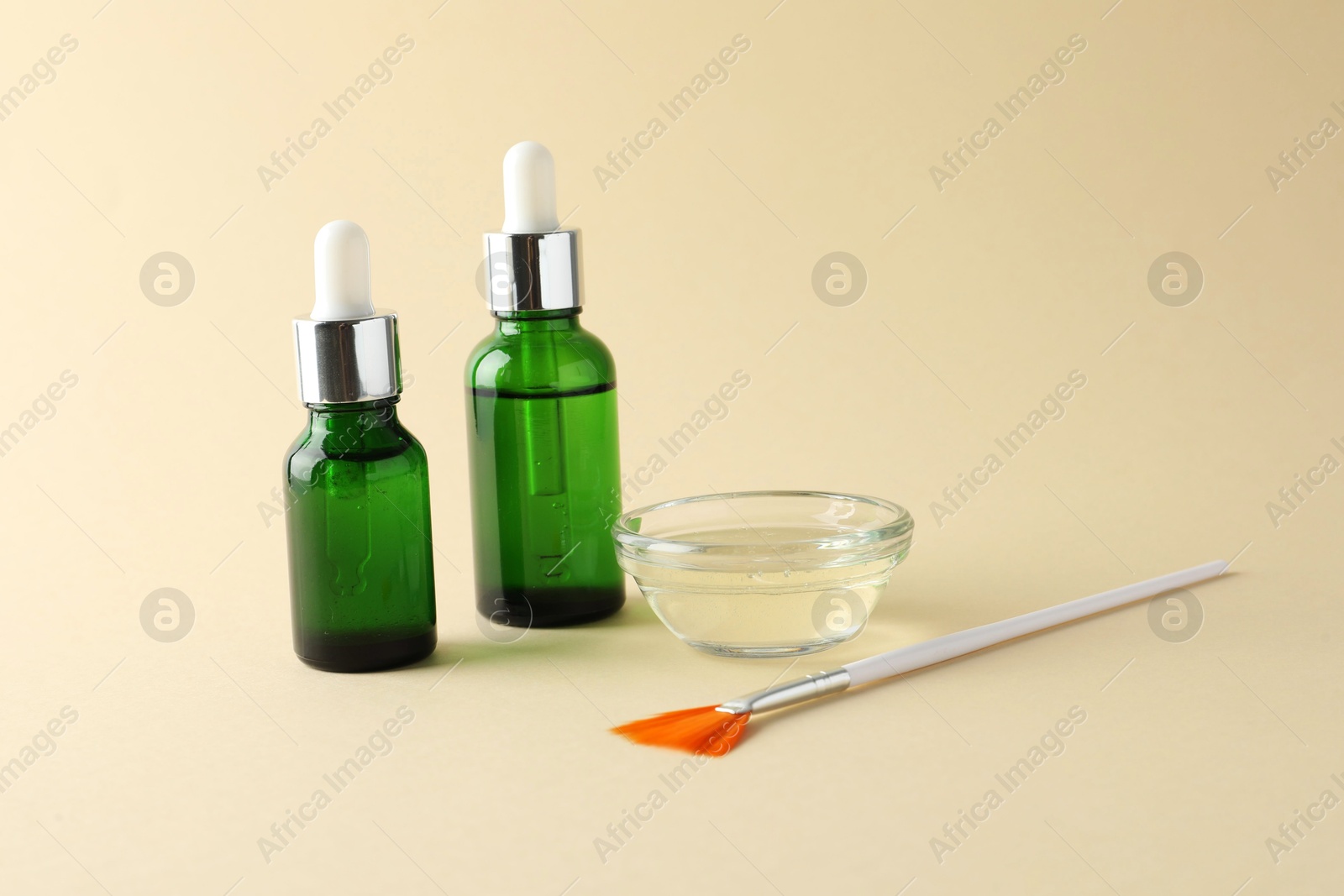 Photo of Bottles of chemical peel, bowl with liquid and brush on beige background. Peeling procedure