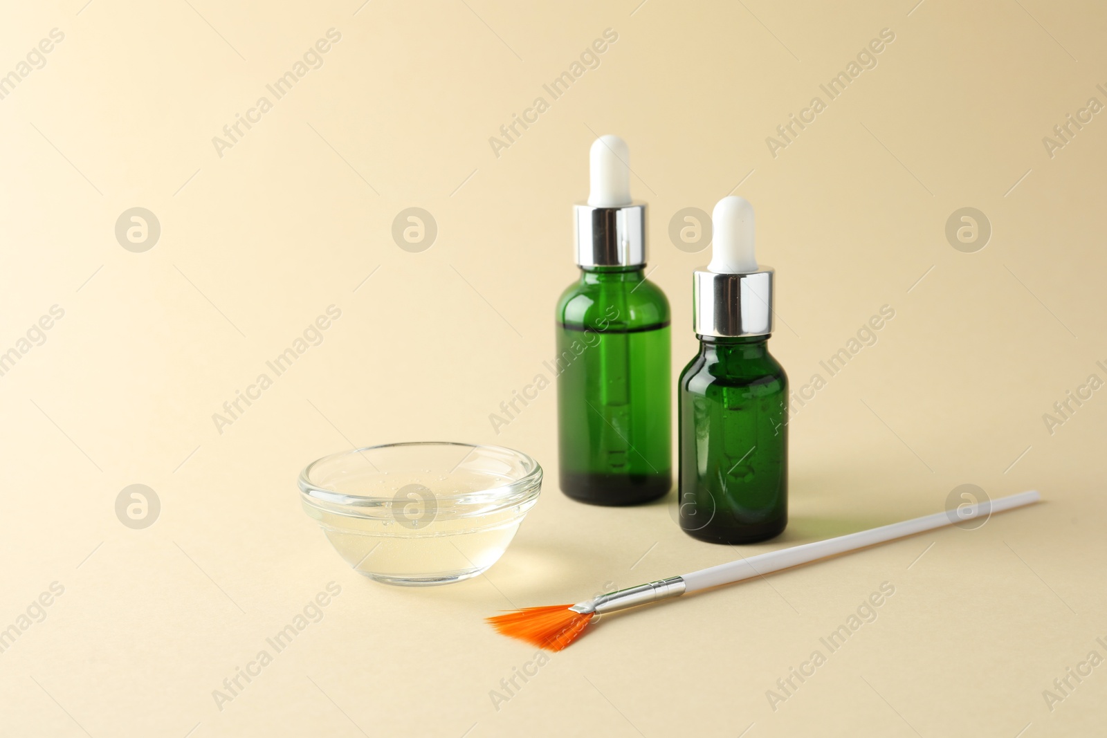 Photo of Bottles of chemical peel, bowl with liquid and brush on beige background. Peeling procedure