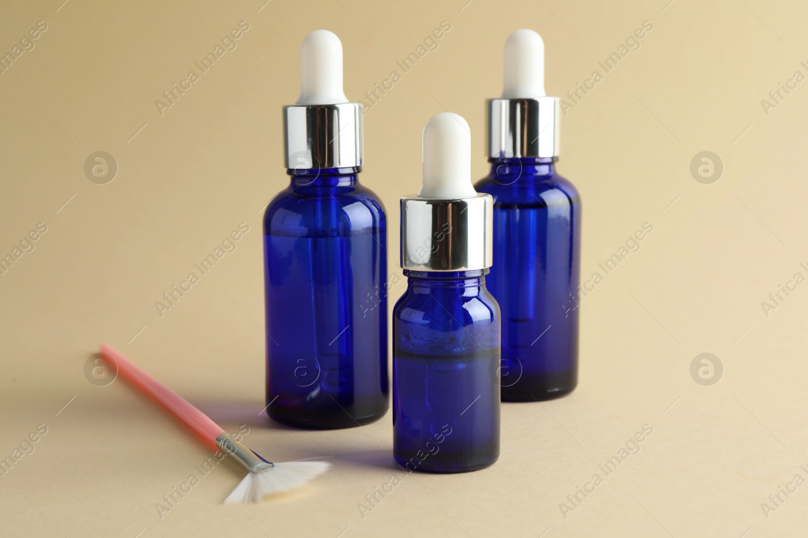 Photo of Bottles of chemical peel and brush on beige background. Peeling procedure