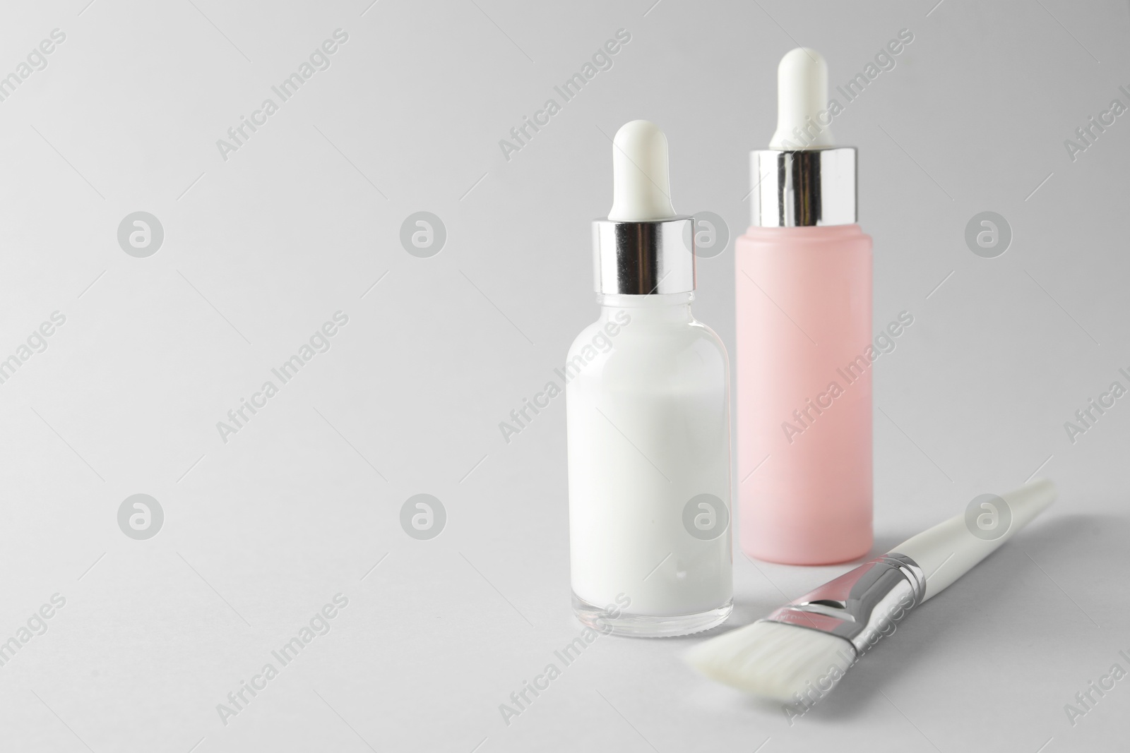 Photo of Bottles of chemical peel and brush on light background, space for text. Peeling procedure