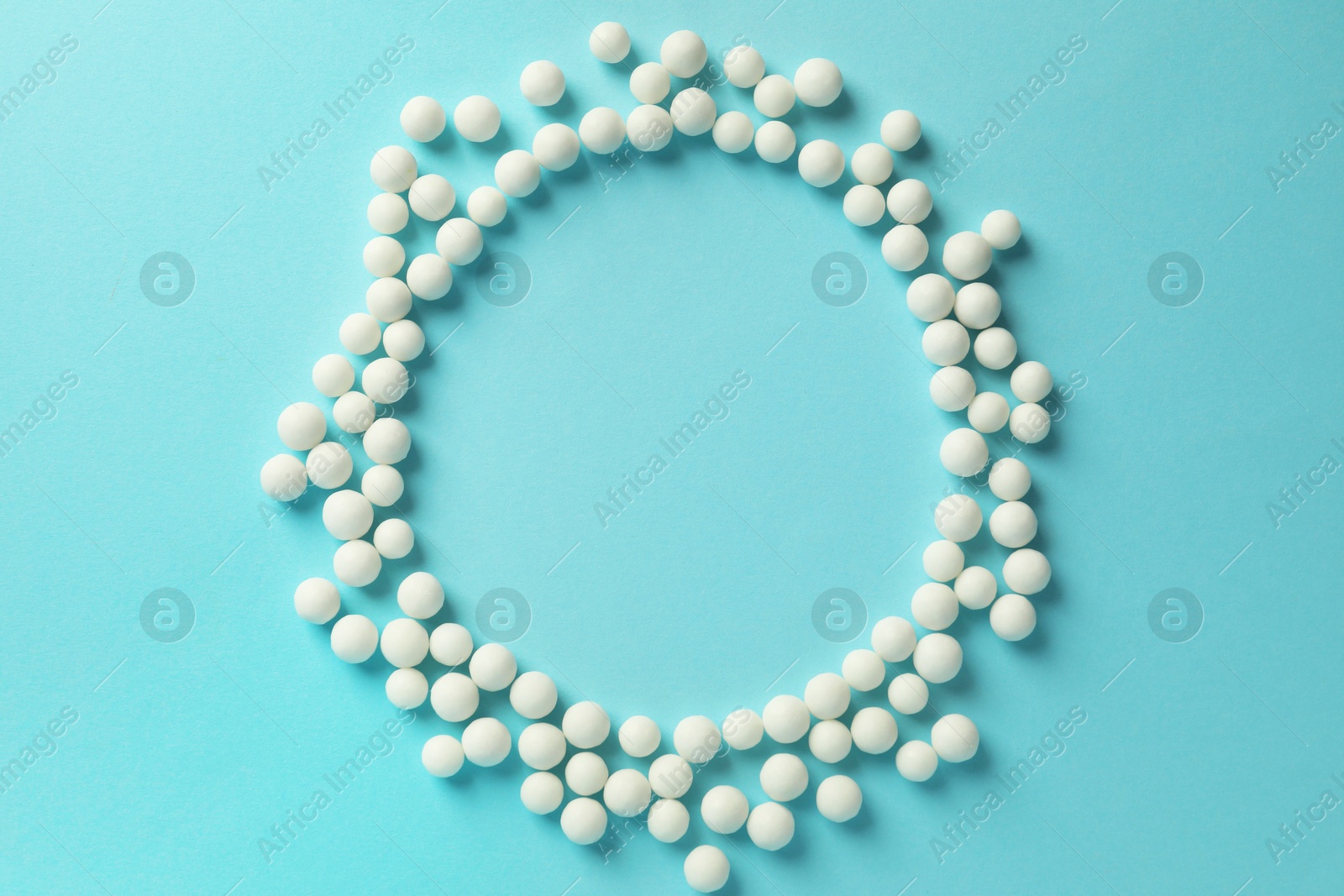 Photo of Homeopathy. Frame made of pills on light blue background, top view. Space for text