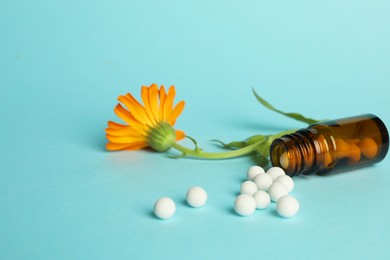 Photo of Homeopathy. Bottle with pills and calendula flower on light blue background